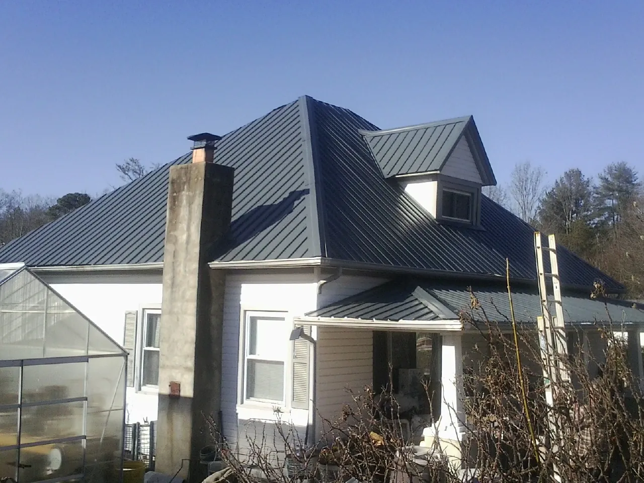 Dark blue standing seam metal roof on a white farmhouse with dormer — Slate & Tile Roof Repair by Roofing Brothers in Star