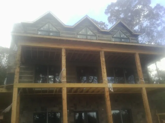 Dormers and porch framing on a large log home under construction — Roof Coating work by our crew in Star