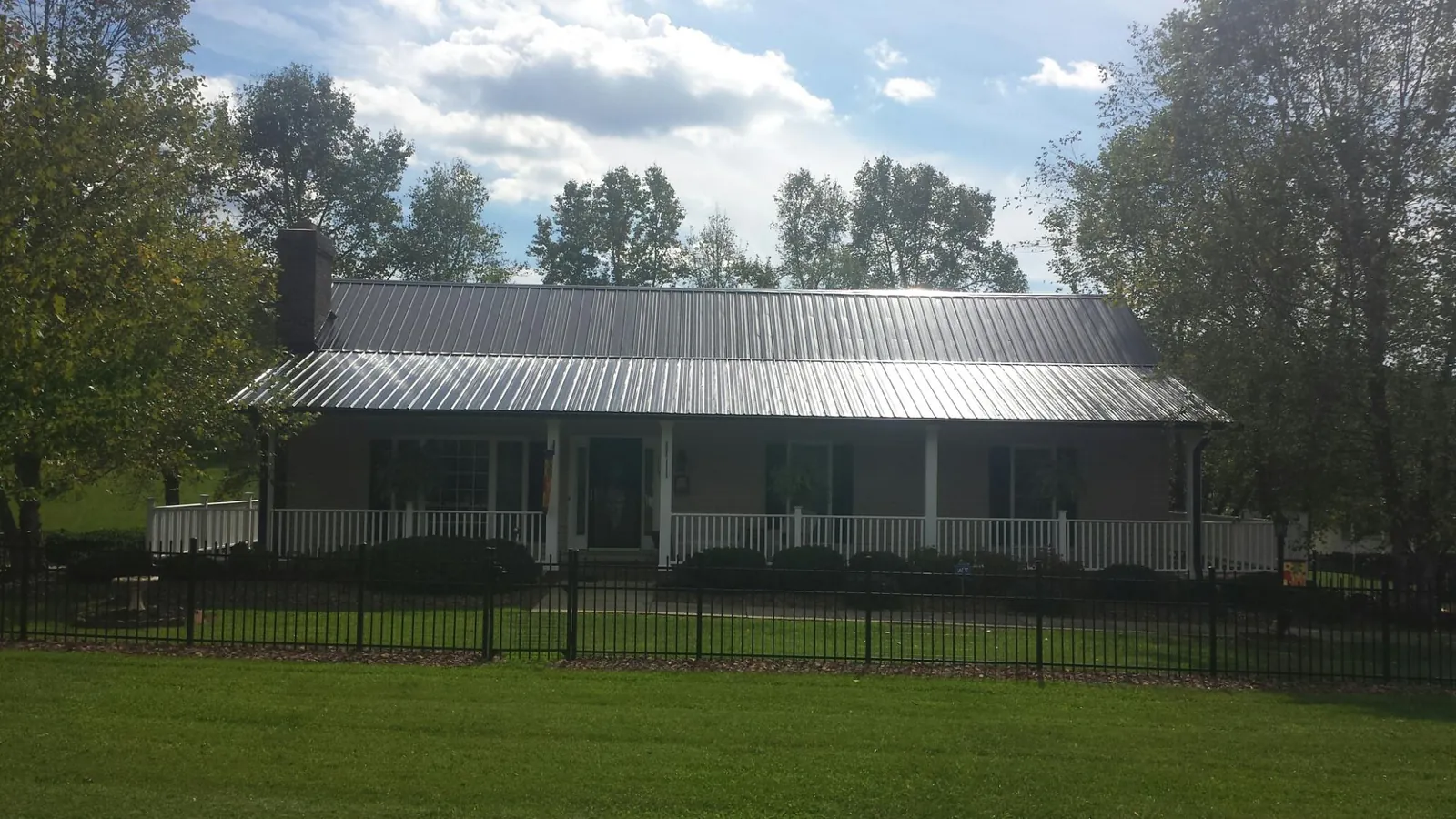 Gray metal roof on a brick ranch with a full width front porch — Gutter Guard Installation work by our crew in Star
